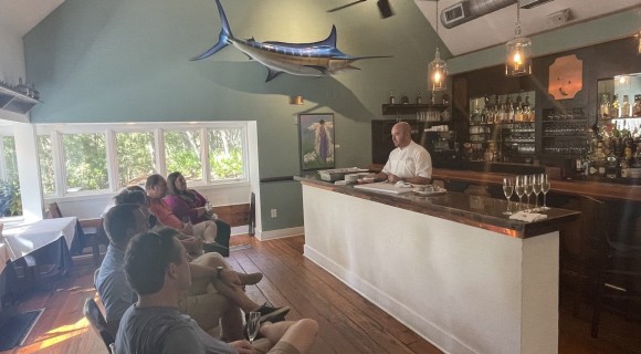 Alexander's chef at the bar during the cooking demo with a row of onlookers watching