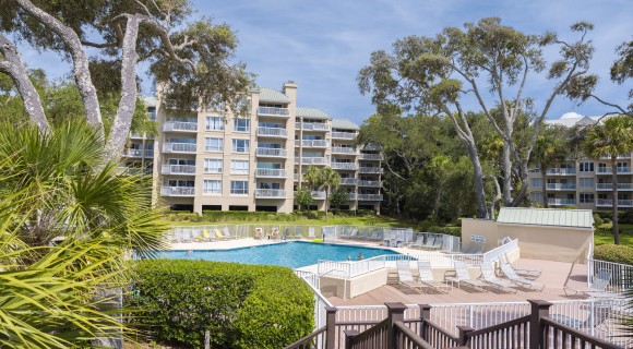 community pool surrounded by lawn chairs and villa buildings