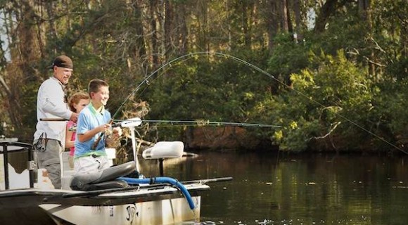 Two young kids fishing with adult on boat