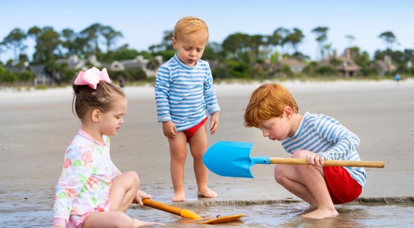 three small children digging on the beach