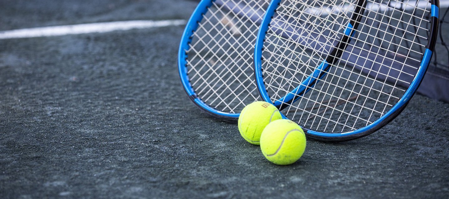 Close up of two tennis rackets and two tennis balls on clay court