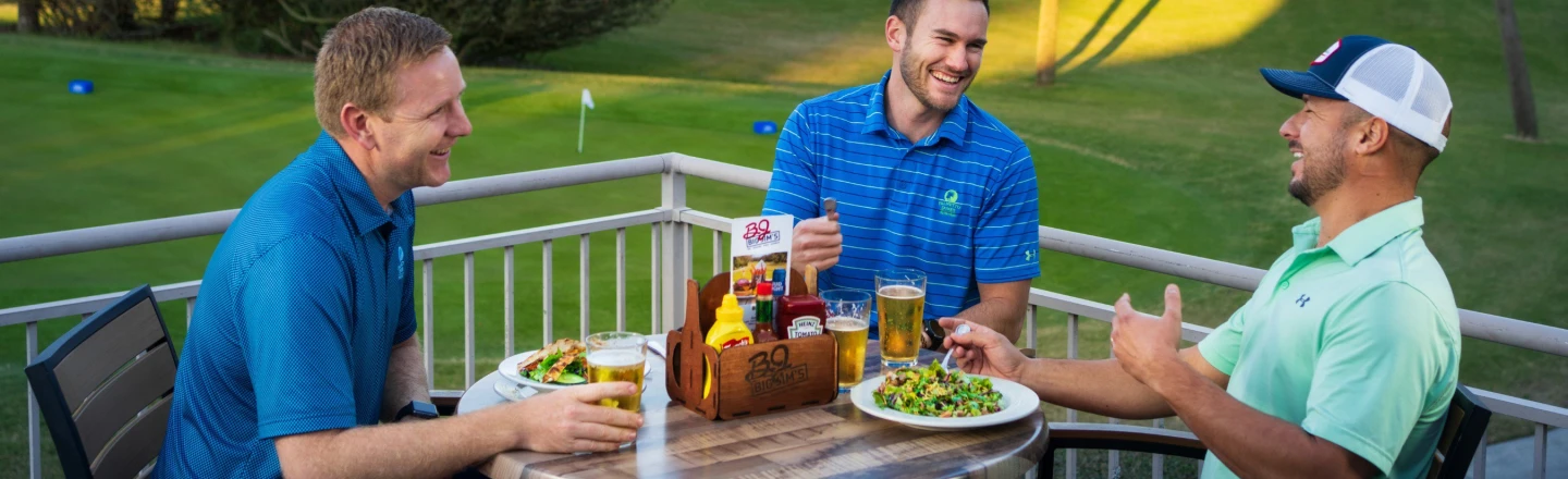 Three young golfers enjoying lunch and beers on outdoor patio at Big Jim's restaurant.