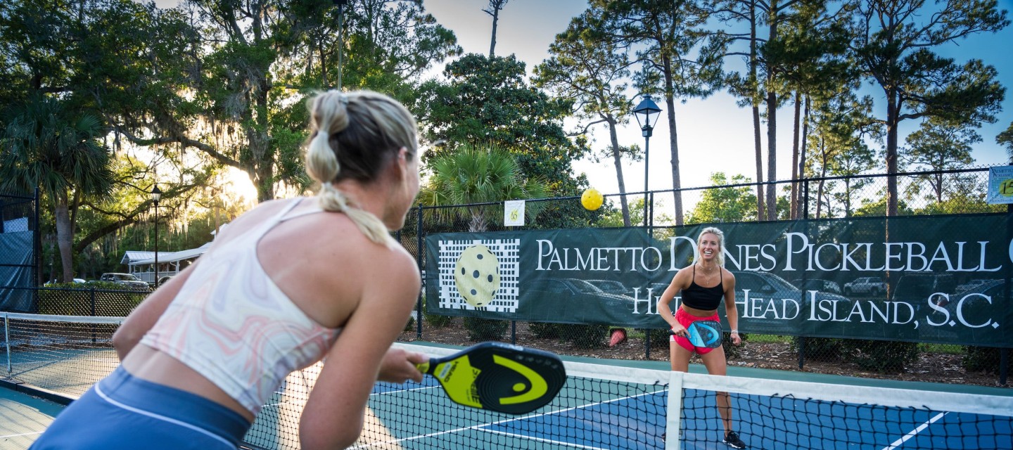 two women playing pickleball with sun in the background at Palmetto Dunes Pickleball Center