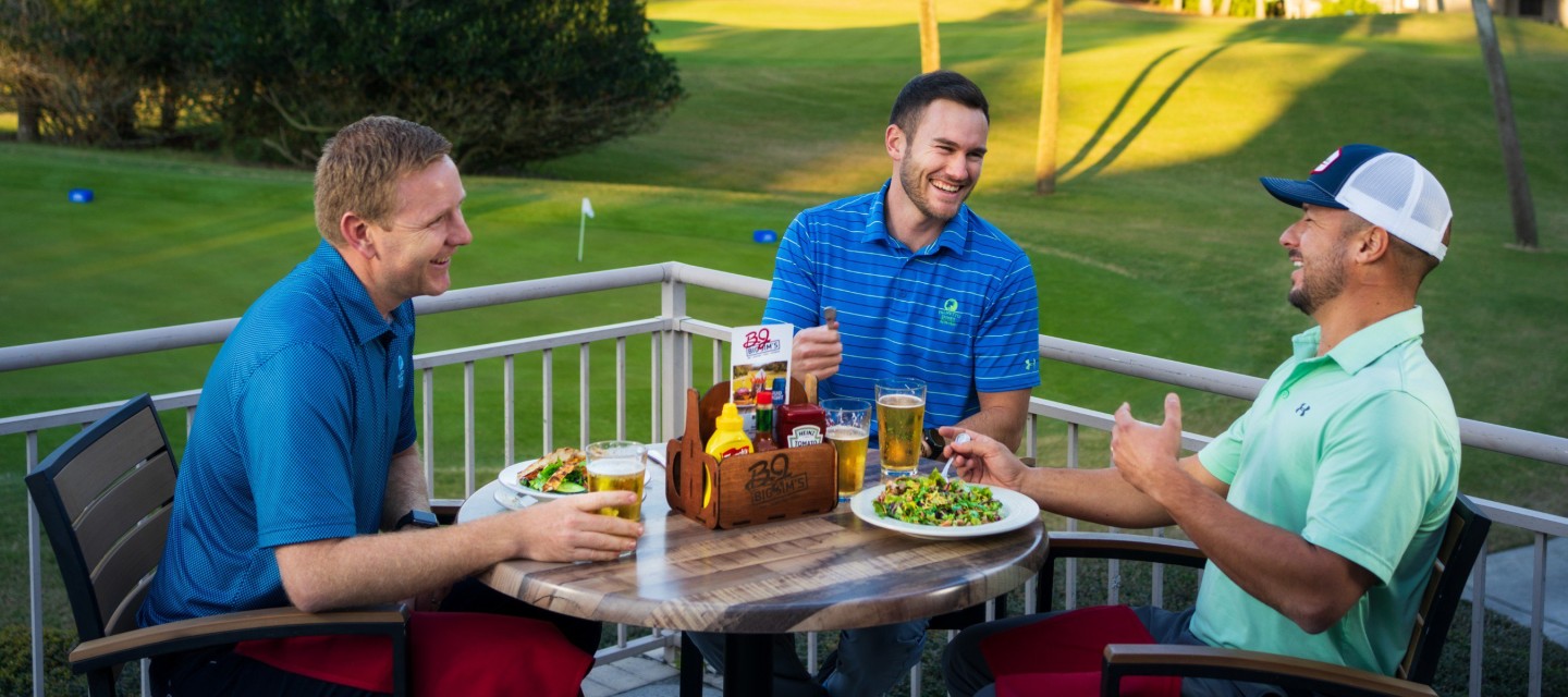 Three young golfers enjoying lunch and beers on outdoor patio at Big Jim's restaurant.