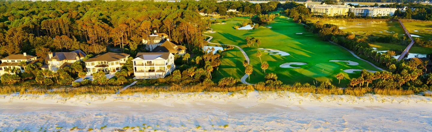 Aerial shot of ocean, beach, golf course, and vacation rental properties