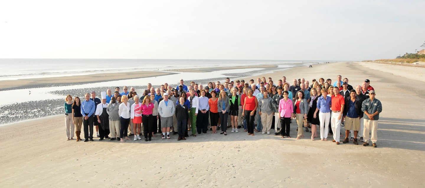 Large group of Palmetto Dunes employees smiling on beach