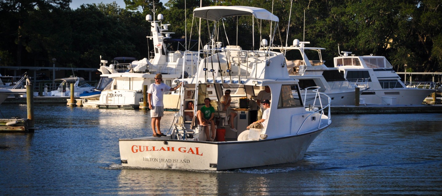 Fishing boat in marina with several people aboard